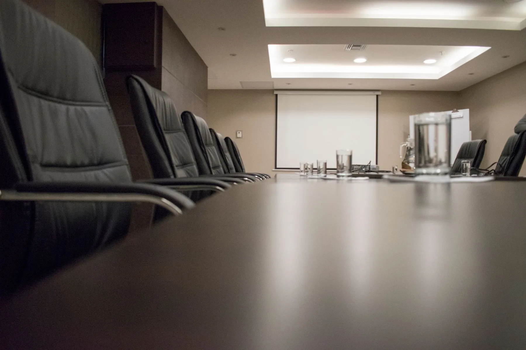 An empty conference room with black chairs around a long table