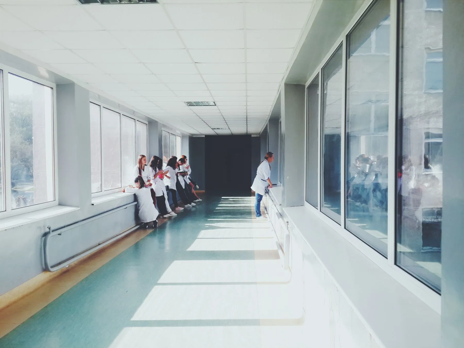 A bright hospital corridor with clinical staff in white coats