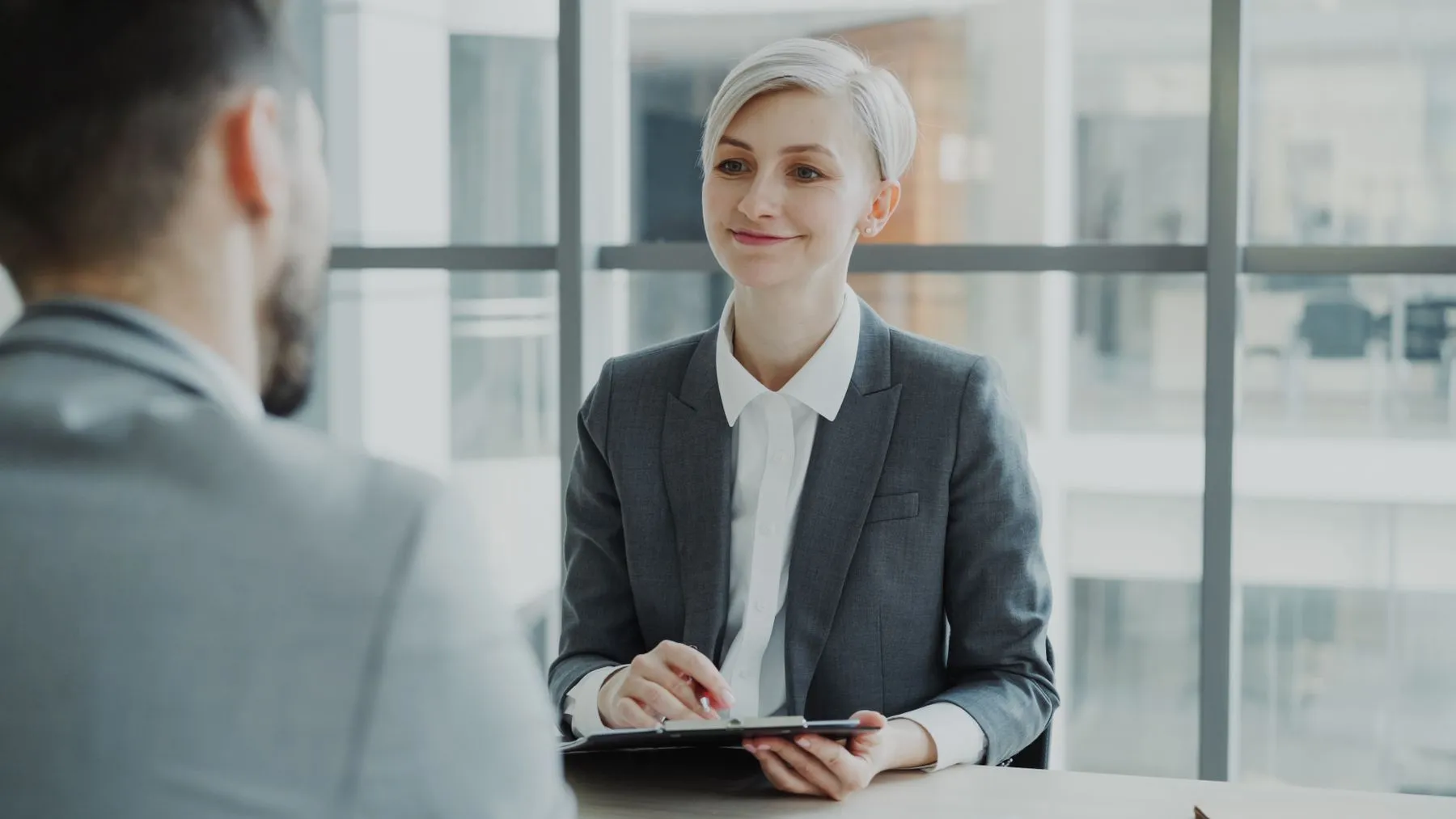 An interviewer taking notes across a desk from a candidate